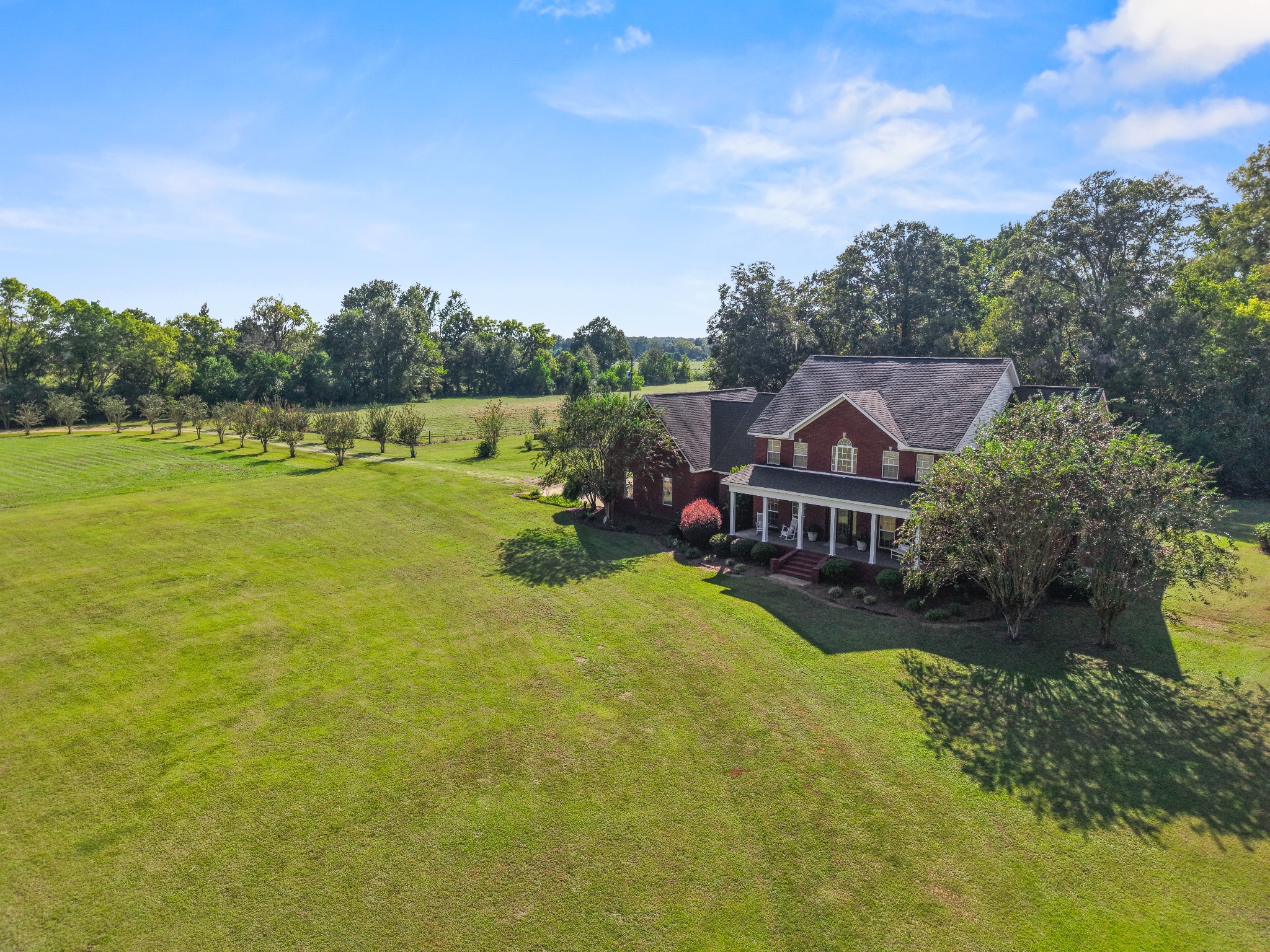 Aerial view of a brick home surrounded by lawns and trees